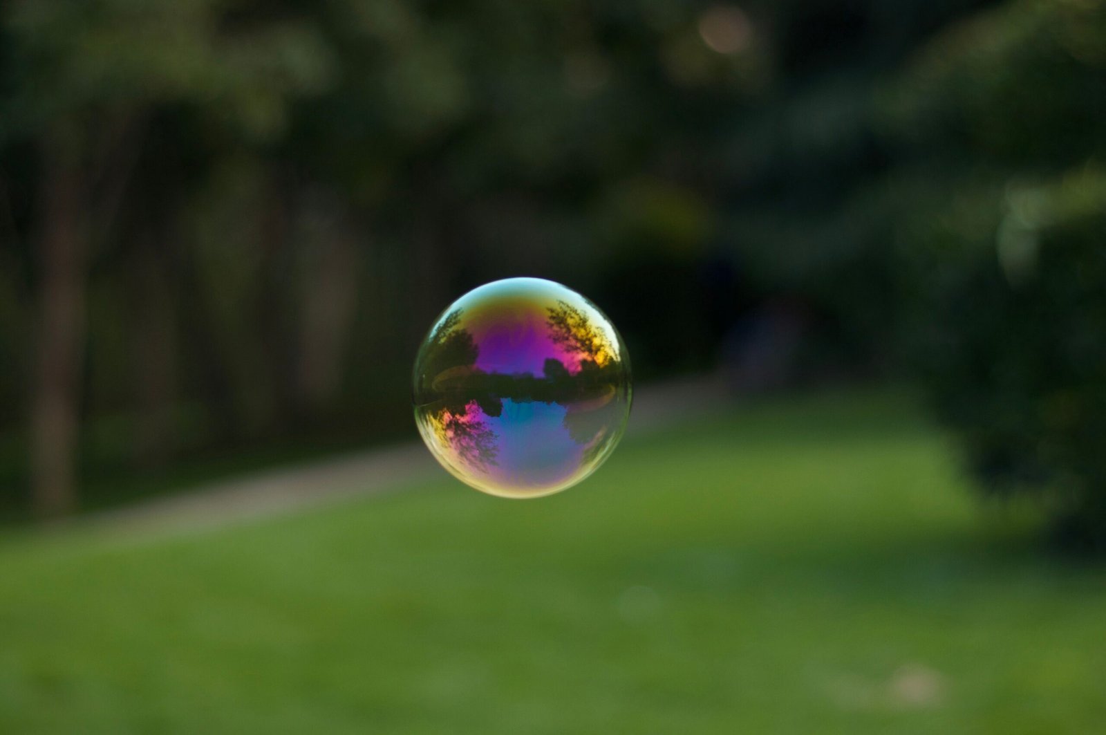 A vibrant soap bubble floating outdoors with a colorful reflection of the surroundings.