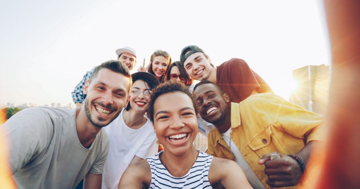 A diverse group of friends taking a joyful selfie outdoors during sunset.