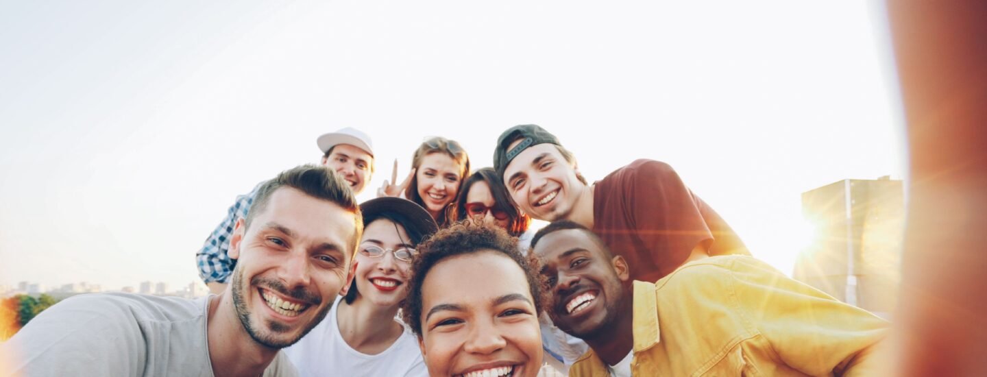 A diverse group of friends taking a joyful selfie outdoors during sunset.