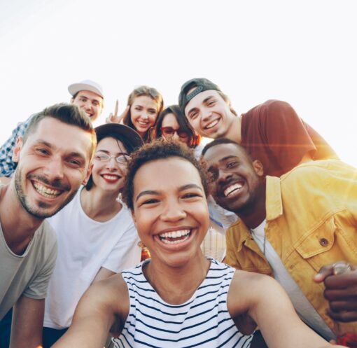 A diverse group of friends taking a joyful selfie outdoors during sunset.
