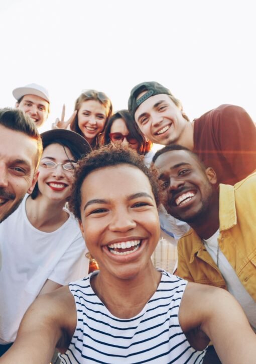 A diverse group of friends taking a joyful selfie outdoors during sunset.