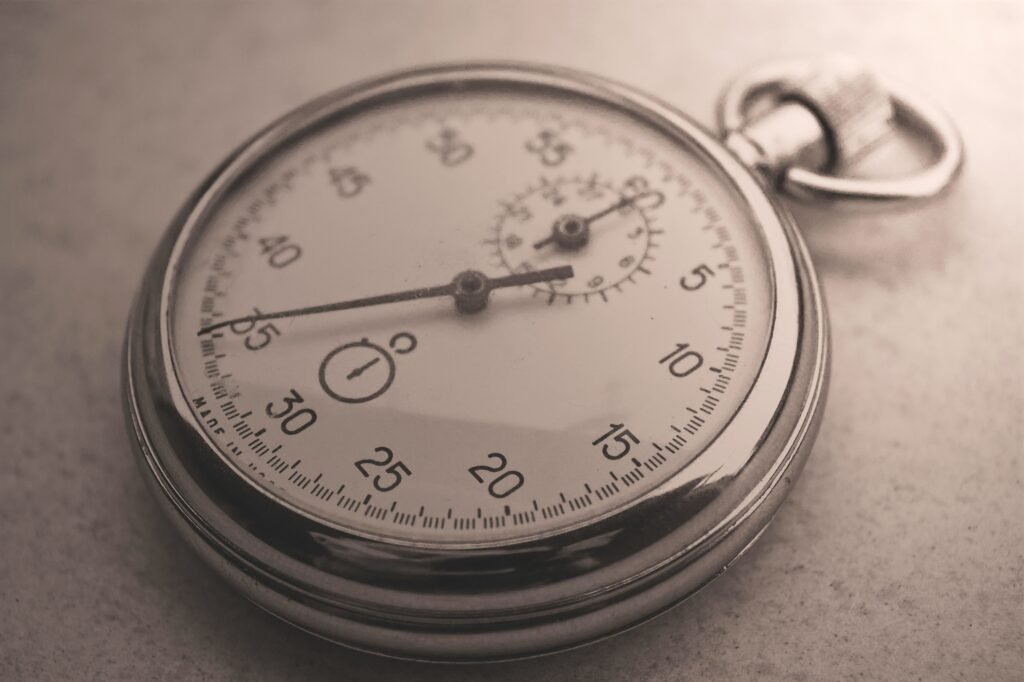 An antique silver pocket watch captured in a sepia tone, showcasing intricate details.