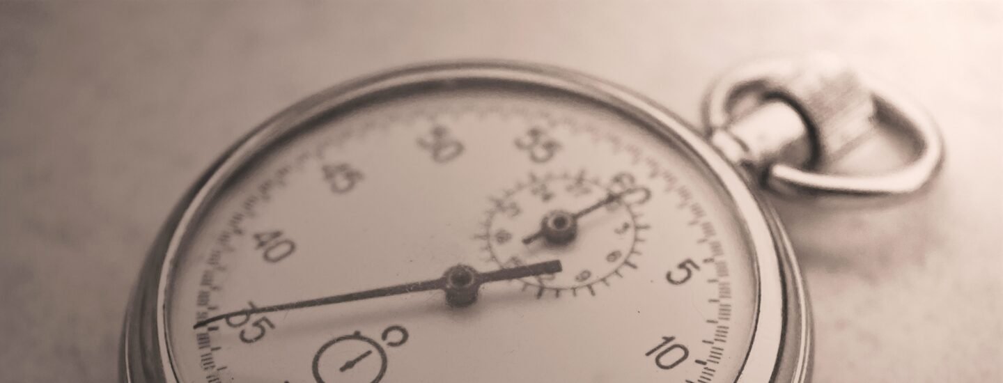 An antique silver pocket watch captured in a sepia tone, showcasing intricate details.