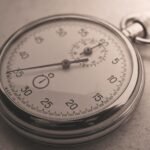 An antique silver pocket watch captured in a sepia tone, showcasing intricate details.