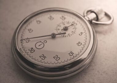 An antique silver pocket watch captured in a sepia tone, showcasing intricate details.