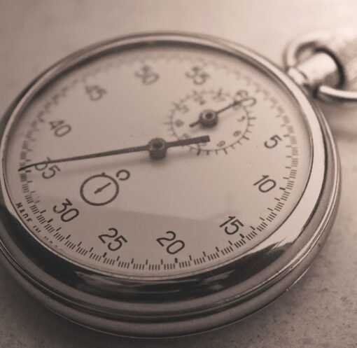 An antique silver pocket watch captured in a sepia tone, showcasing intricate details.