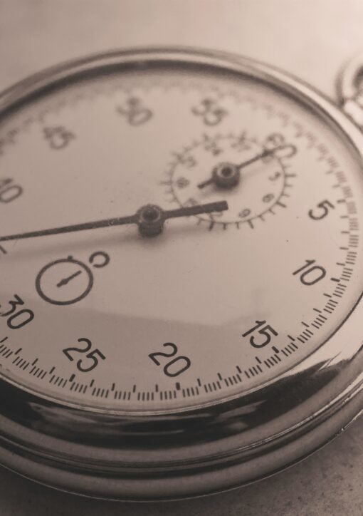 An antique silver pocket watch captured in a sepia tone, showcasing intricate details.