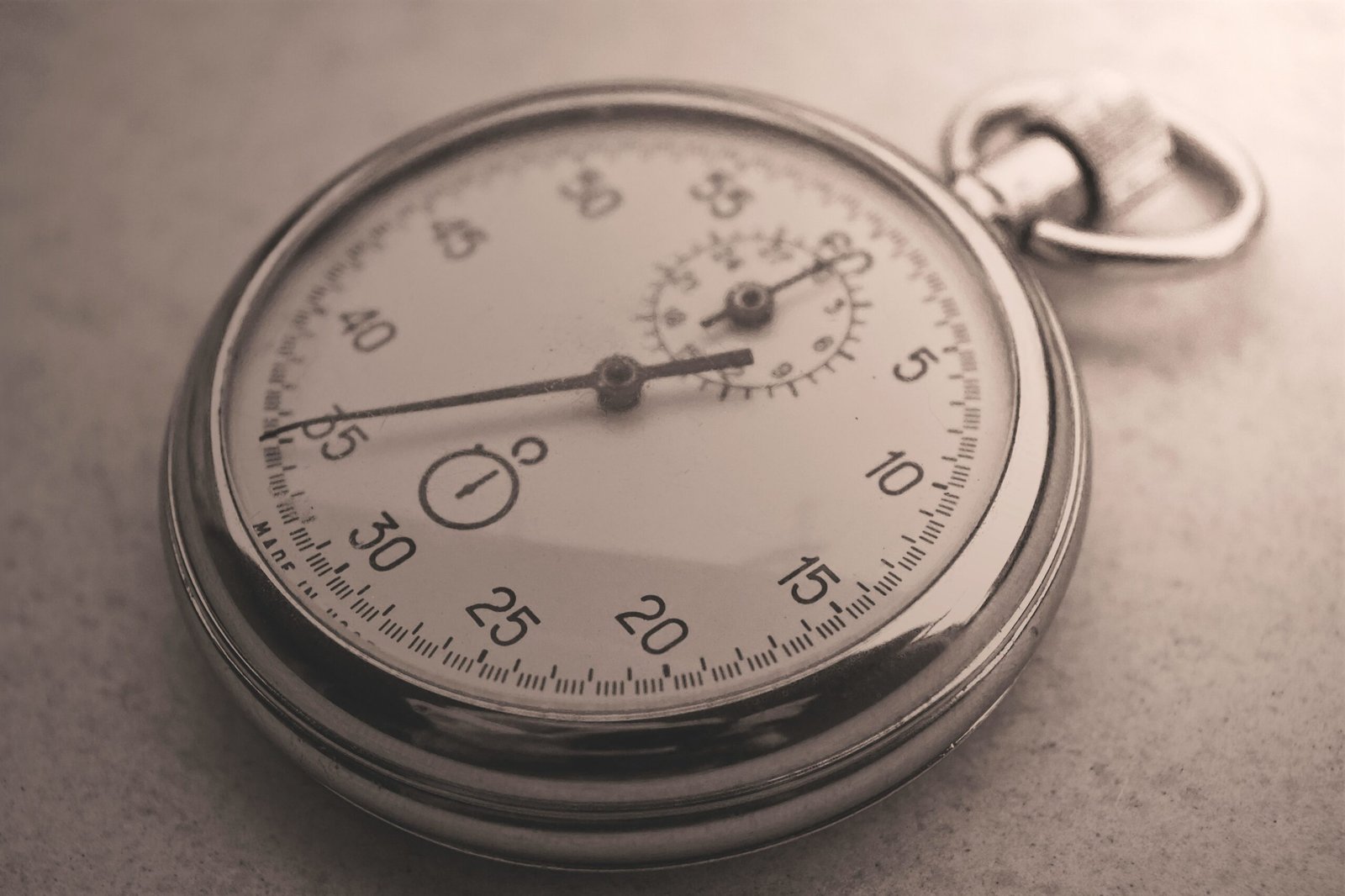 An antique silver pocket watch captured in a sepia tone, showcasing intricate details.