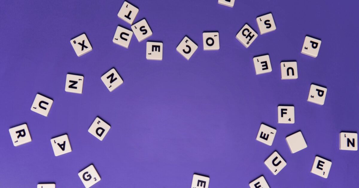 Alphabet tiles scattered on a purple background, perfect for creative projects.