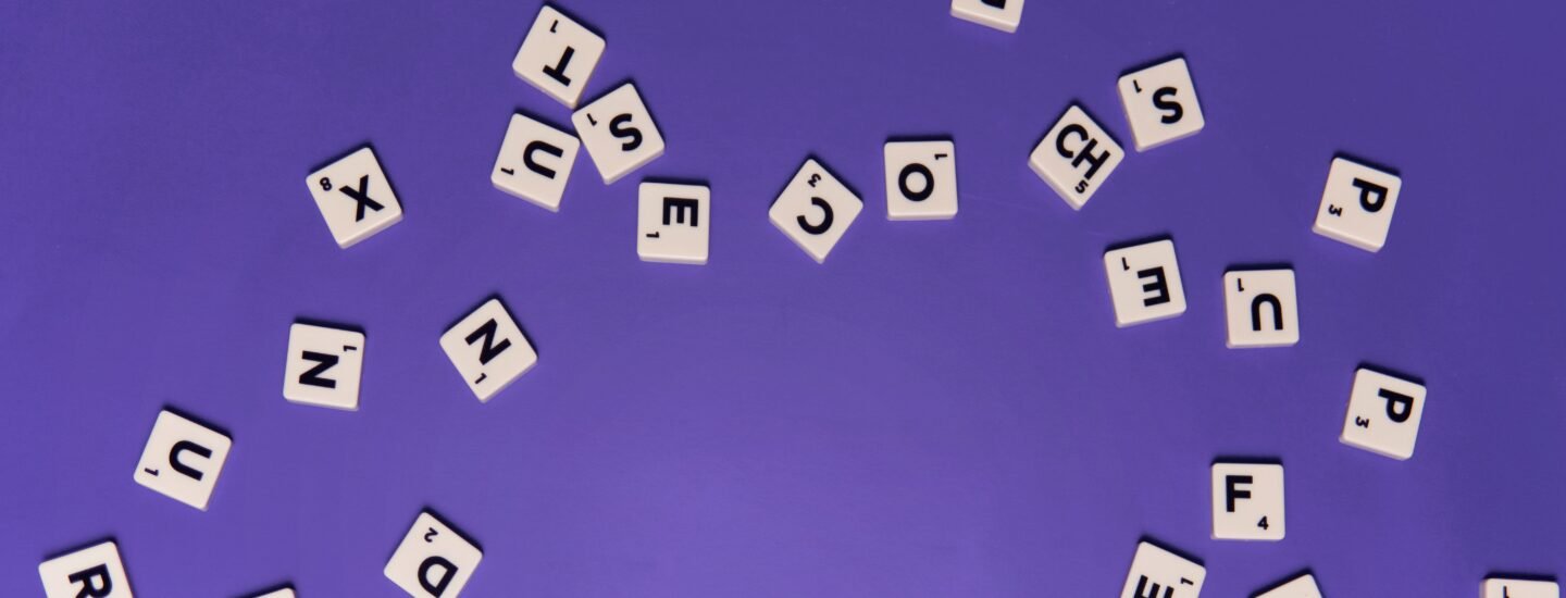 Alphabet tiles scattered on a purple background, perfect for creative projects.