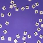 Alphabet tiles scattered on a purple background, perfect for creative projects.