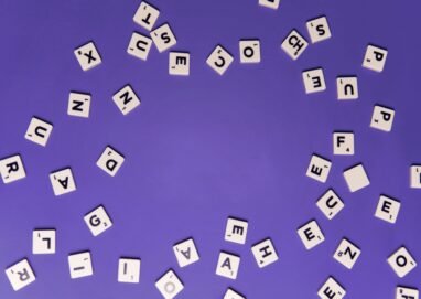 Alphabet tiles scattered on a purple background, perfect for creative projects.