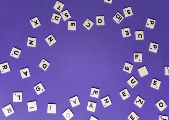 Alphabet tiles scattered on a purple background, perfect for creative projects.