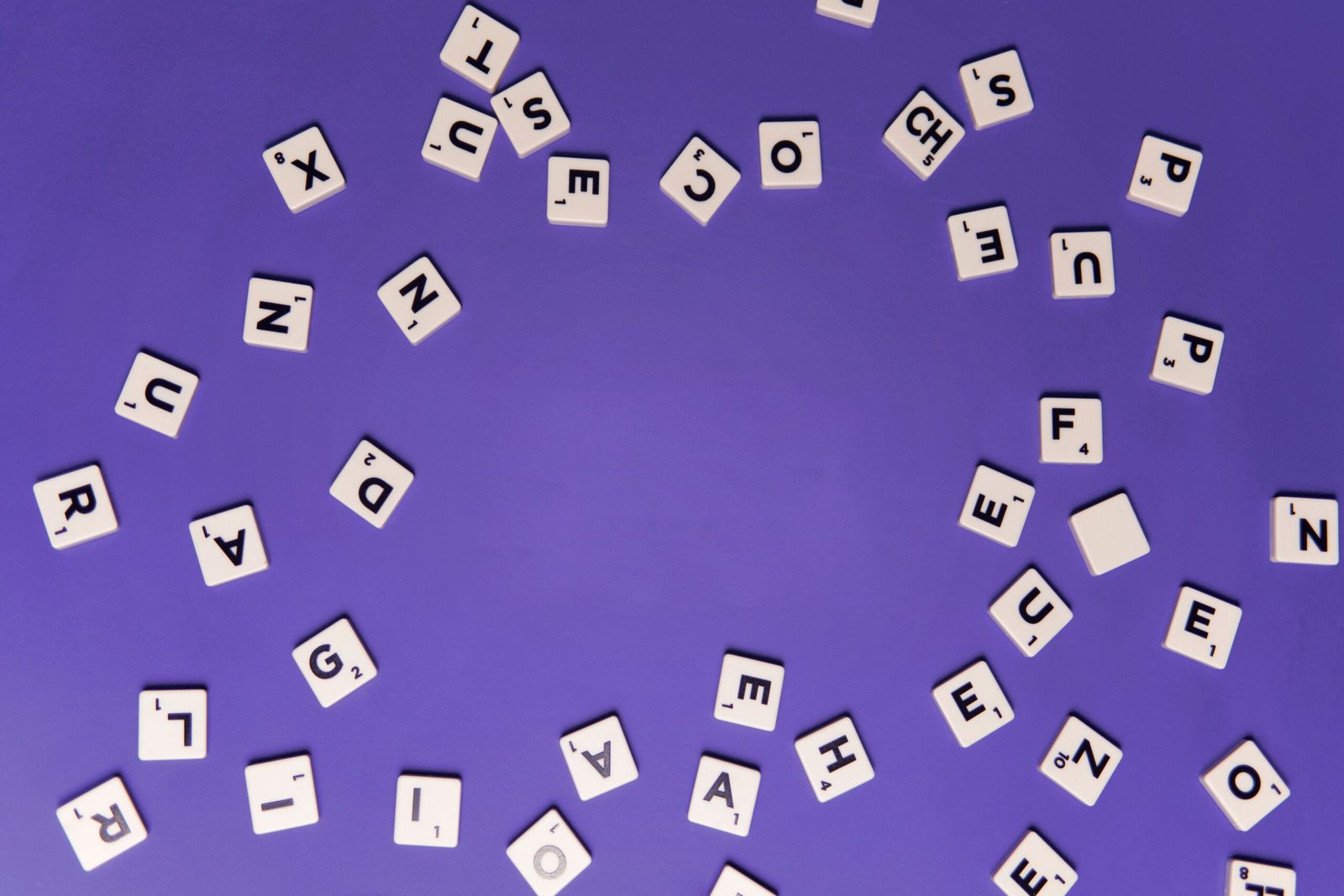 Alphabet tiles scattered on a purple background, perfect for creative projects.