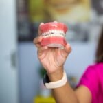 A dentist's hand holding a dental teeth model indoors. Ideal for dental care concepts.