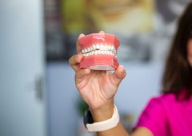 A dentist's hand holding a dental teeth model indoors. Ideal for dental care concepts.