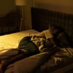A person sleeping peacefully in a cozy bedroom with soft lighting, creating a serene ambiance.
