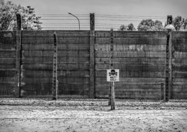 Monochrome image of Auschwitz Birkenau fence with warning sign in Poland.