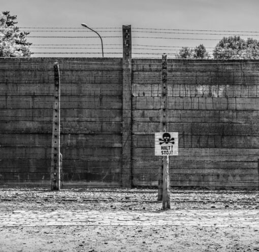 Monochrome image of Auschwitz Birkenau fence with warning sign in Poland.