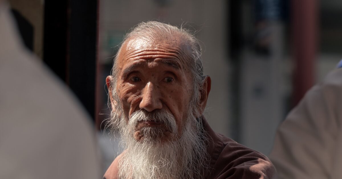 Close-up of a senior man with long beard in a Tokyo street, reflecting tradition and wisdom.