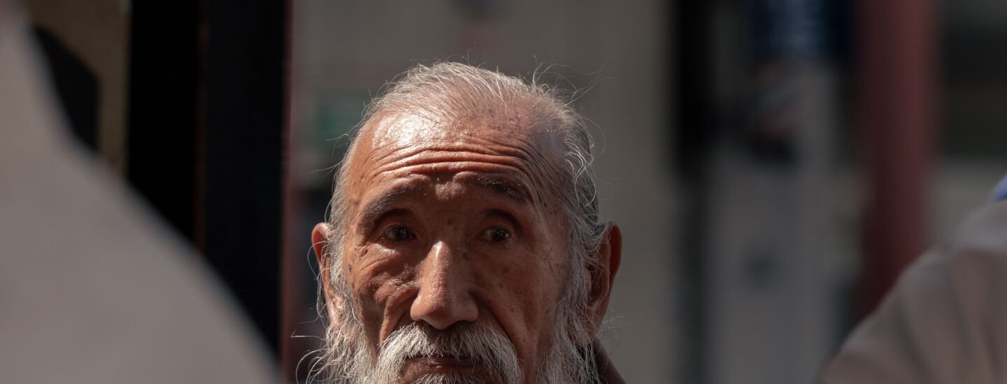 Close-up of a senior man with long beard in a Tokyo street, reflecting tradition and wisdom.