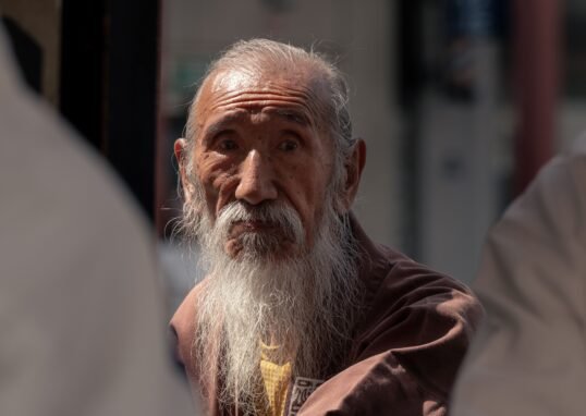 Close-up of a senior man with long beard in a Tokyo street, reflecting tradition and wisdom.